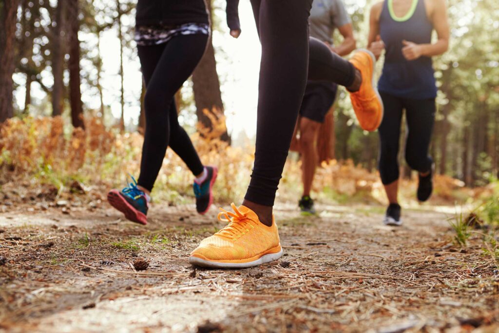 Runners with orange sneakers running on a trail in the woods